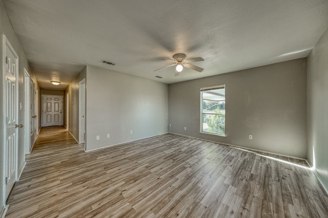 empty room featuring light hardwood / wood-style floors, ceiling fan, and a textured ceiling