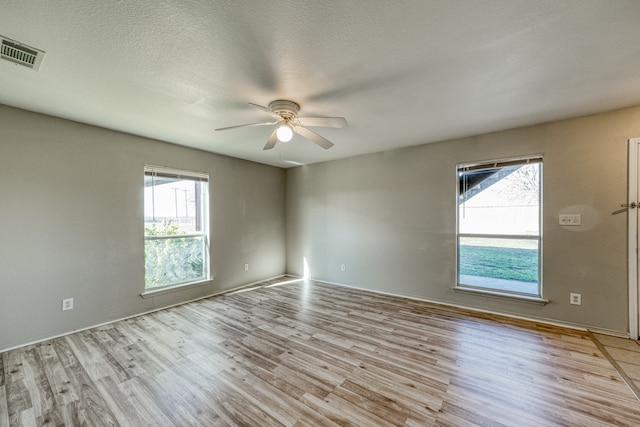 unfurnished room featuring light wood-type flooring, a textured ceiling, ceiling fan, and plenty of natural light