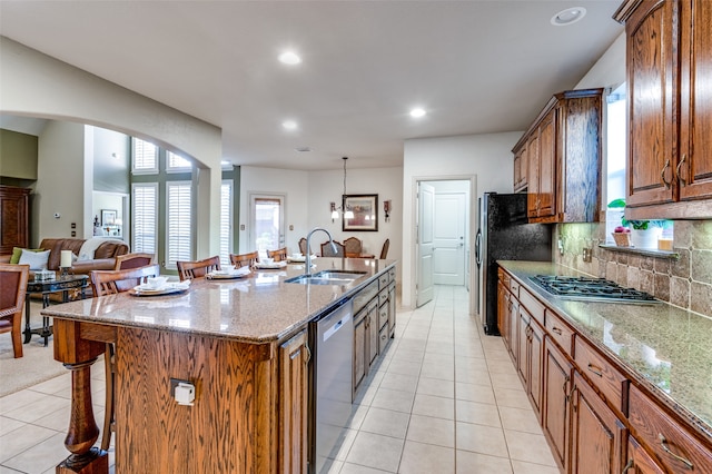 kitchen with appliances with stainless steel finishes, decorative backsplash, sink, a kitchen breakfast bar, and a kitchen island with sink