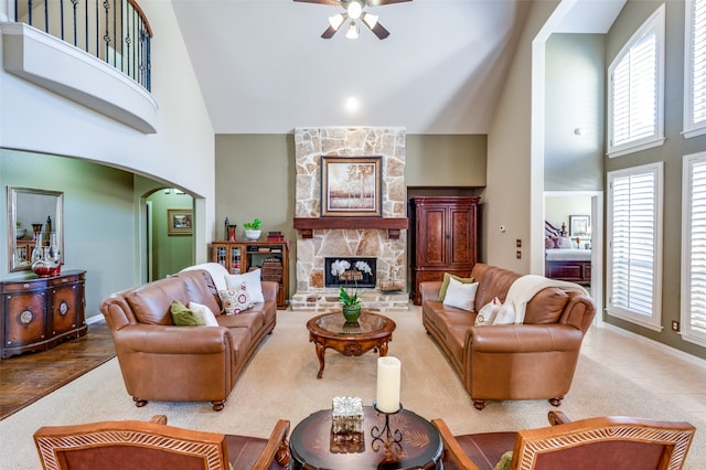 living room featuring high vaulted ceiling, wood-type flooring, ceiling fan, and a fireplace