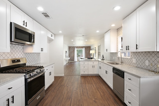 kitchen with decorative backsplash, sink, white cabinets, appliances with stainless steel finishes, and dark hardwood / wood-style flooring