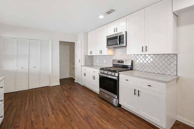 kitchen with appliances with stainless steel finishes, white cabinets, and dark hardwood / wood-style flooring