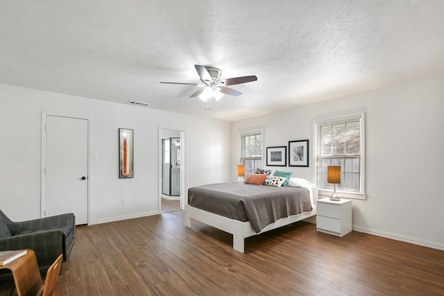 bedroom with ceiling fan, a textured ceiling, dark hardwood / wood-style flooring, and ensuite bath