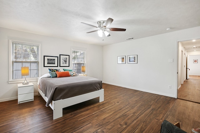 bedroom with ceiling fan, multiple windows, and dark hardwood / wood-style floors