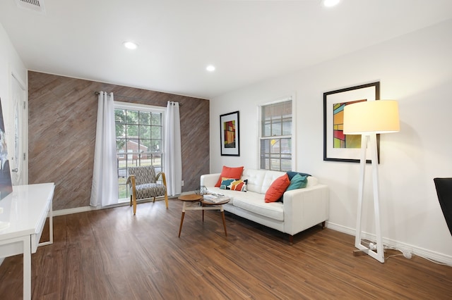 living room with dark wood-type flooring and wooden walls