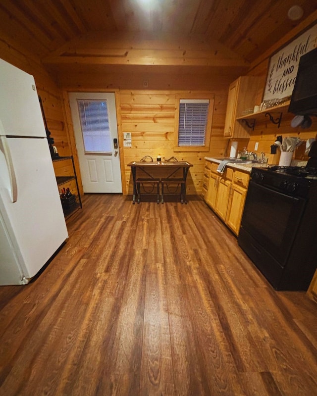 kitchen with wood-type flooring, vaulted ceiling, white fridge, black stove, and light brown cabinetry