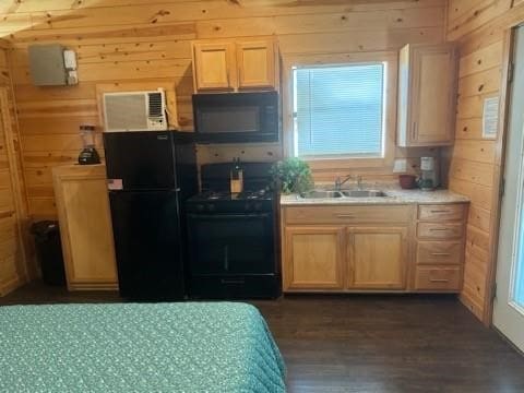 kitchen with black appliances, dark hardwood / wood-style floors, wood walls, light brown cabinets, and sink