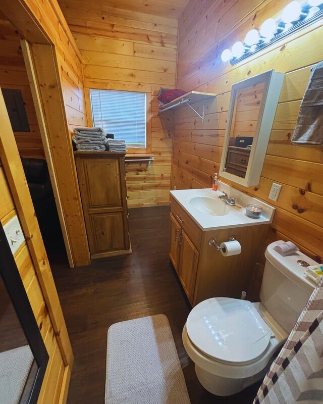 bathroom with wood walls, toilet, vanity, and wood-type flooring