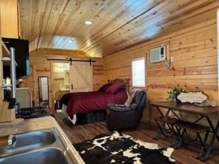 bedroom featuring wooden walls, a barn door, hardwood / wood-style flooring, and wood ceiling