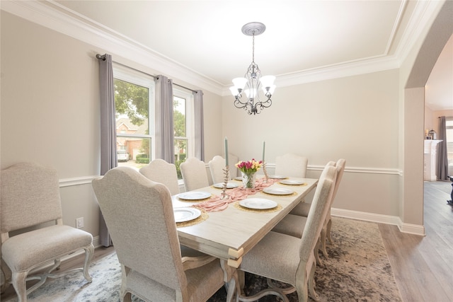 dining space with crown molding, light hardwood / wood-style flooring, and a notable chandelier