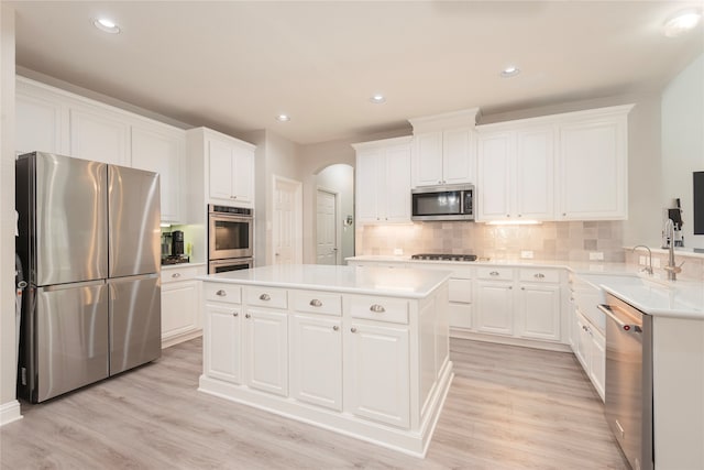 kitchen with a center island, appliances with stainless steel finishes, light hardwood / wood-style flooring, and white cabinets