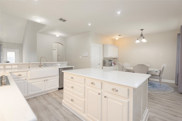 kitchen with a kitchen island, sink, decorative light fixtures, white cabinetry, and light hardwood / wood-style floors