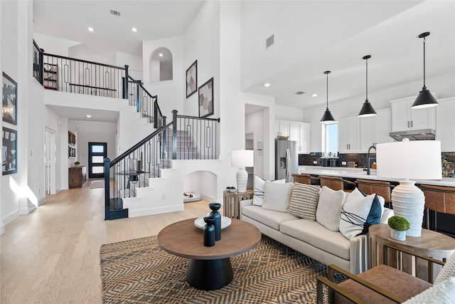 living room featuring a towering ceiling and light hardwood / wood-style floors