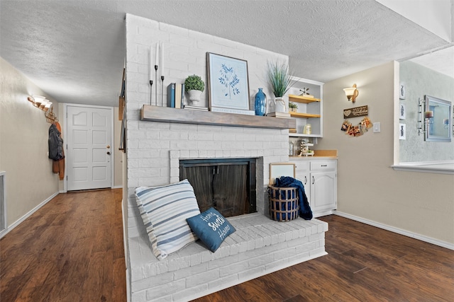 living room featuring built in features, dark wood-type flooring, a textured ceiling, and a brick fireplace