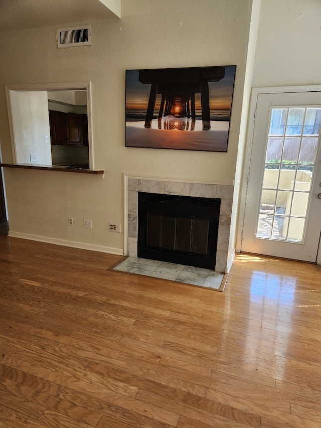 unfurnished living room featuring light wood-type flooring and a high end fireplace