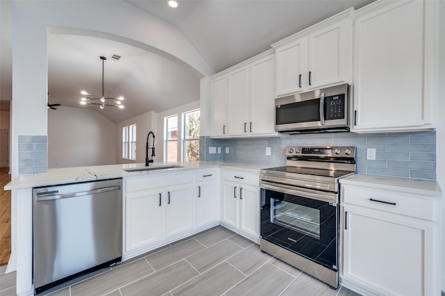 kitchen featuring sink, vaulted ceiling, a notable chandelier, white cabinetry, and appliances with stainless steel finishes