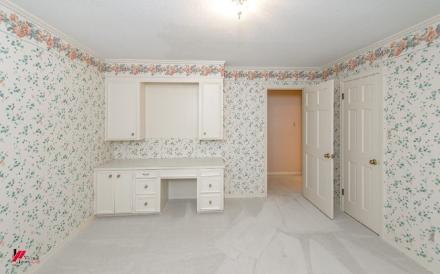 unfurnished office with ornamental molding, built in desk, a textured ceiling, and light colored carpet