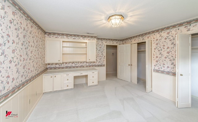 interior space featuring built in desk and light colored carpet