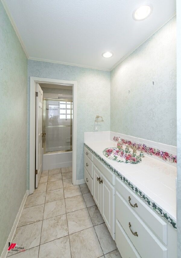 bathroom featuring crown molding, combined bath / shower with glass door, and vanity