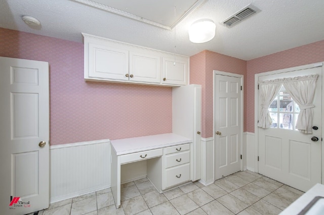 interior space with a textured ceiling and built in desk