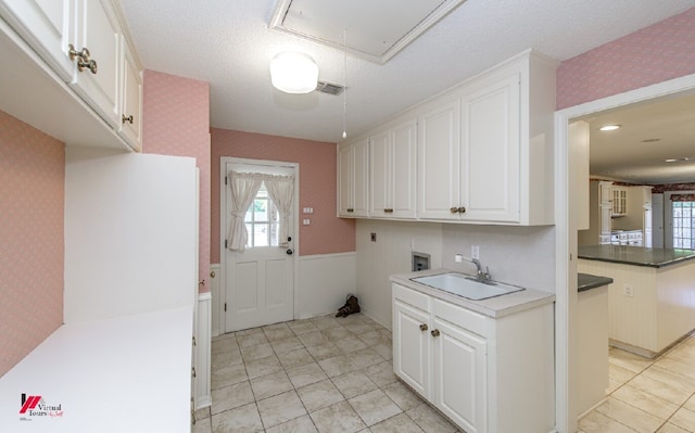 kitchen with white cabinets, a textured ceiling, and sink