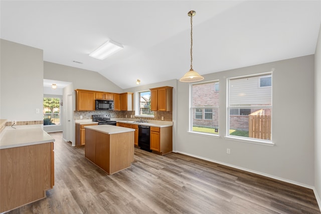 kitchen featuring vaulted ceiling, black appliances, plenty of natural light, and hardwood / wood-style floors