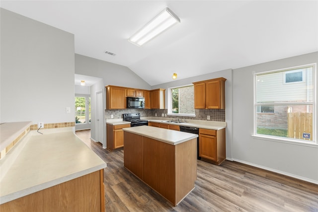 kitchen with lofted ceiling, black appliances, a wealth of natural light, and wood-type flooring