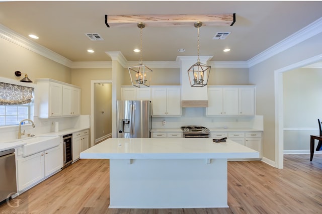 kitchen with light hardwood / wood-style flooring, stainless steel appliances, hanging light fixtures, and a kitchen island