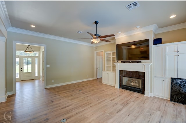 unfurnished living room featuring ornamental molding, a tiled fireplace, and light hardwood / wood-style floors