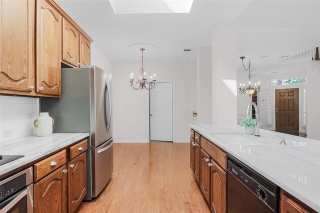 kitchen featuring pendant lighting, light hardwood / wood-style floors, black appliances, and a chandelier