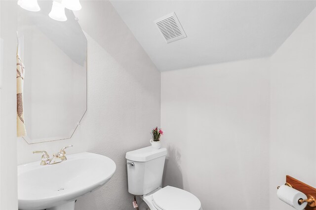 bathroom featuring toilet, lofted ceiling, and sink