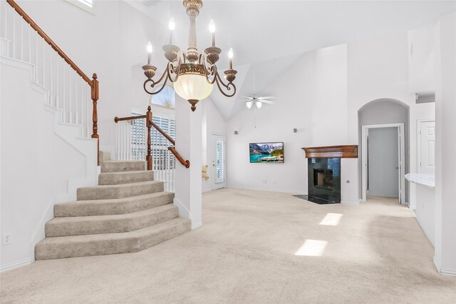 unfurnished living room featuring light colored carpet, high vaulted ceiling, and ceiling fan