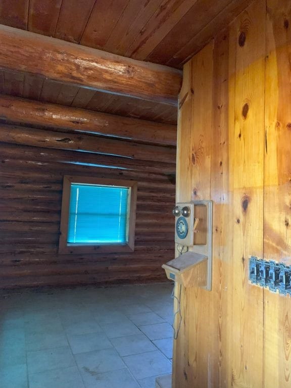 interior space with wood ceiling, rustic walls, and beamed ceiling