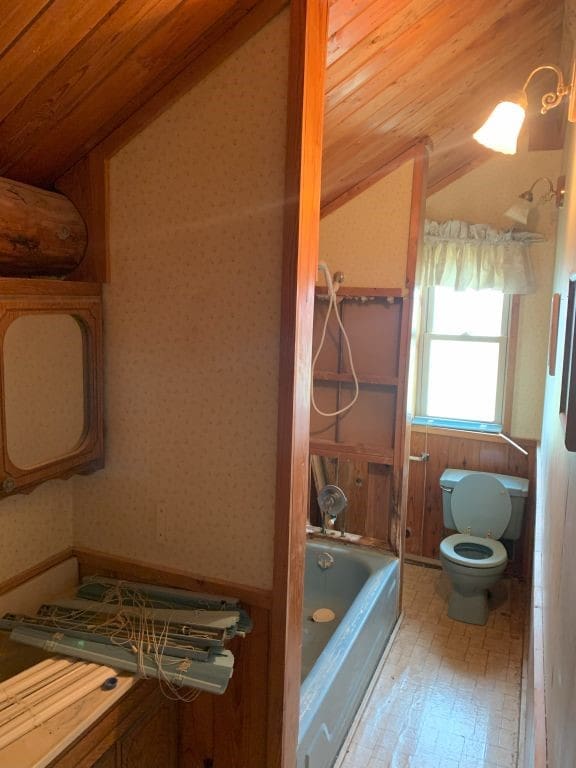 bathroom with lofted ceiling, wood ceiling, wood-type flooring, a tub to relax in, and toilet