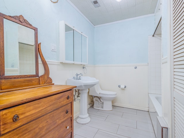 bathroom featuring crown molding, toilet, and bathing tub / shower combination