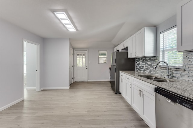 kitchen featuring appliances with stainless steel finishes, light stone counters, a wealth of natural light, sink, and white cabinets