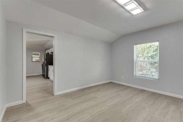 empty room with light wood-type flooring and vaulted ceiling