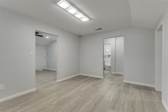 spare room with light hardwood / wood-style floors and vaulted ceiling