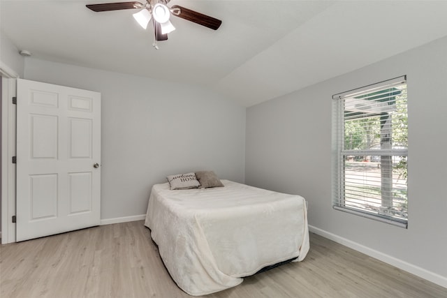 bedroom featuring multiple windows, ceiling fan, light hardwood / wood-style floors, and vaulted ceiling