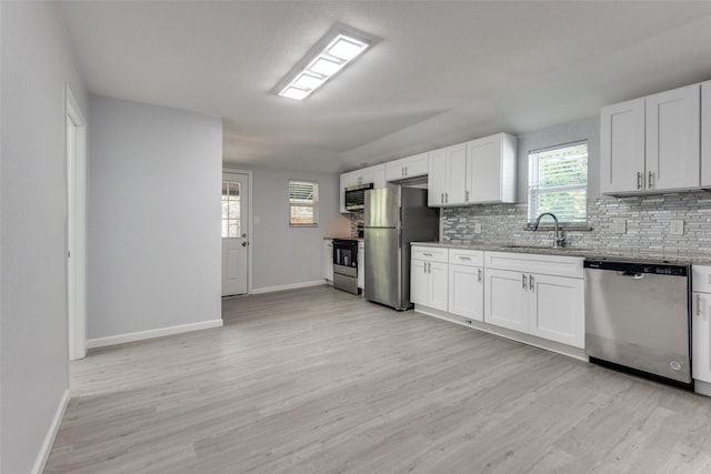 kitchen with stainless steel appliances, white cabinetry, light hardwood / wood-style floors, and sink