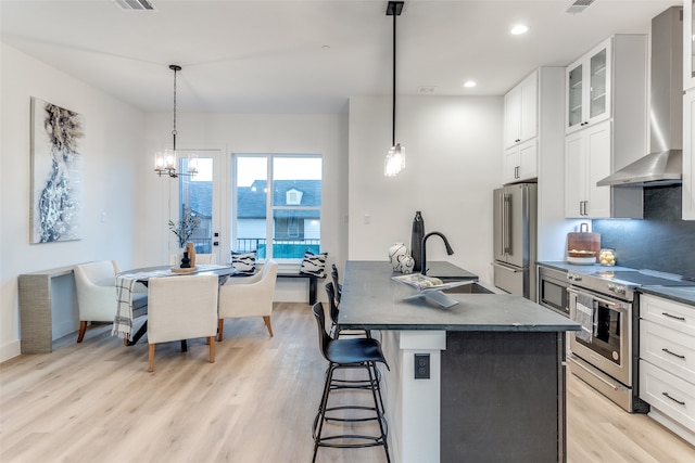 kitchen featuring pendant lighting, white cabinetry, a center island with sink, and appliances with stainless steel finishes