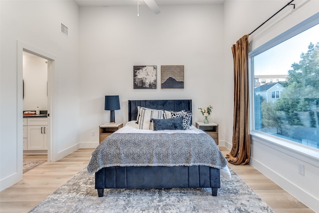 bedroom with ceiling fan, light hardwood / wood-style flooring, and ensuite bathroom