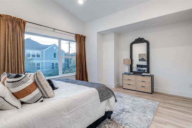 bedroom with light wood-type flooring and vaulted ceiling