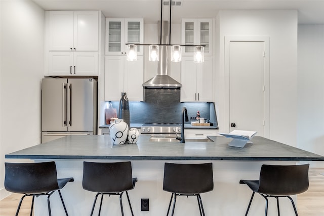 kitchen featuring high end refrigerator, light hardwood / wood-style floors, a breakfast bar, white cabinets, and a large island