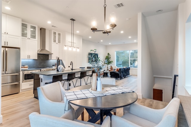 dining room with a notable chandelier, light wood-type flooring, and sink