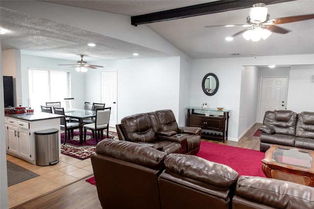 living room featuring light wood-type flooring, a textured ceiling, lofted ceiling with beams, and ceiling fan