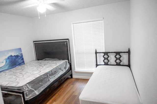 bedroom with ceiling fan, hardwood / wood-style floors, and a textured ceiling