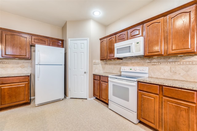 kitchen with light stone counters, tasteful backsplash, and white appliances