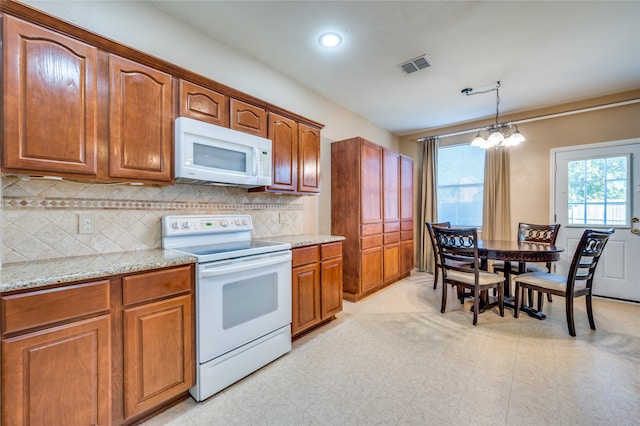 kitchen featuring hanging light fixtures, white appliances, backsplash, a chandelier, and light stone countertops