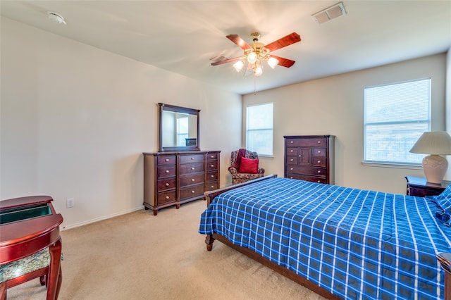 carpeted bedroom featuring multiple windows and ceiling fan